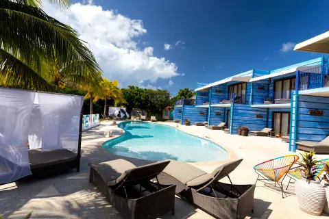 Loungers and a cabana surround the pool by blue buildings at True Blue Bay Resort.