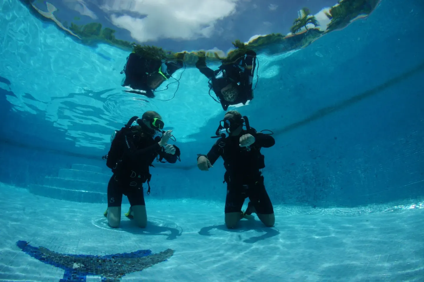 Scuba divers kneeling underwater in a pool at True Blue Bay Resort.