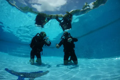 Scuba divers kneeling underwater in a pool at True Blue Bay Resort.