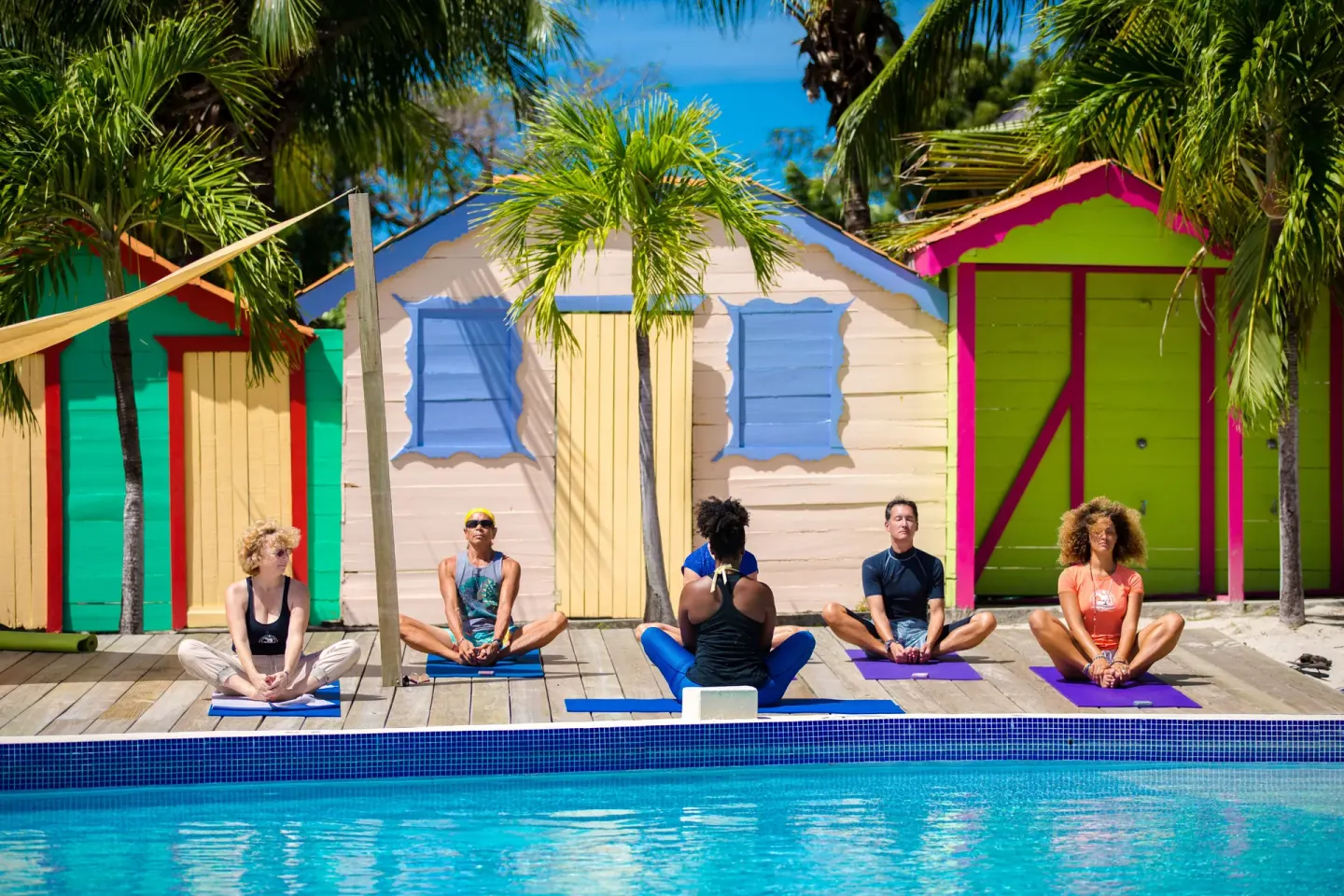 Poolside yoga class beside colorful cabanas at True Blue Bay Resort.