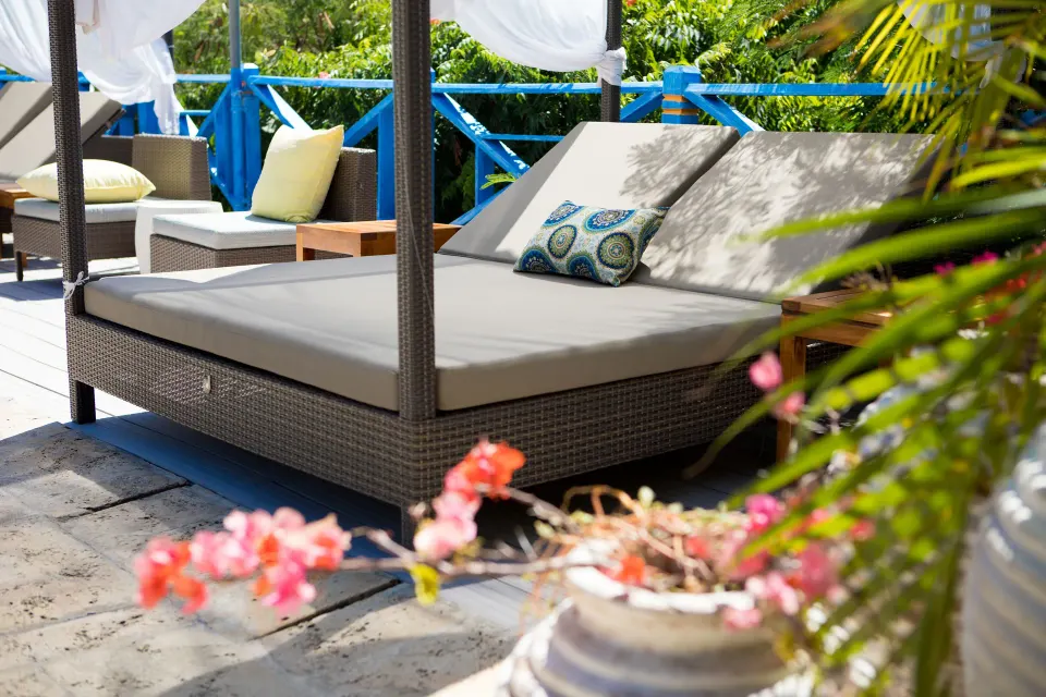 A shaded daybed with pillows sits on a garden terrace at True Blue Bay Resort.