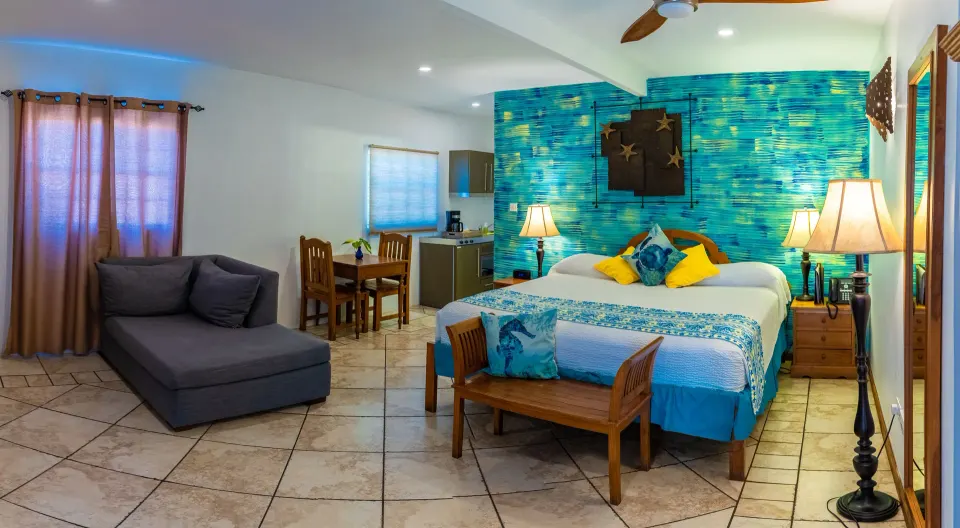 True Blue Bay Resort guest room with bed, sofa, dining table, and kitchenette.