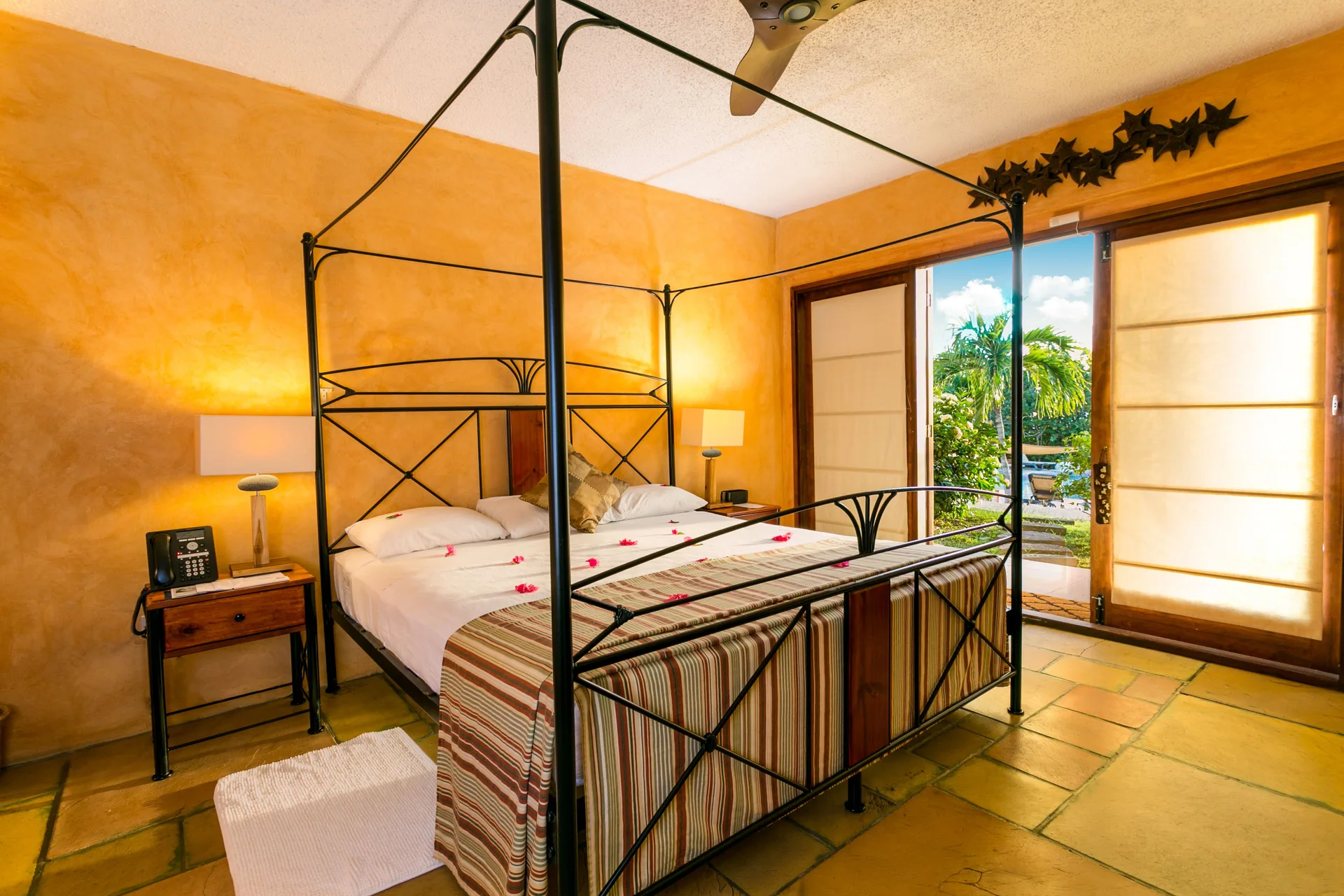 Villa guest room with four-poster bed and garden doors at True Blue Bay Resort.
