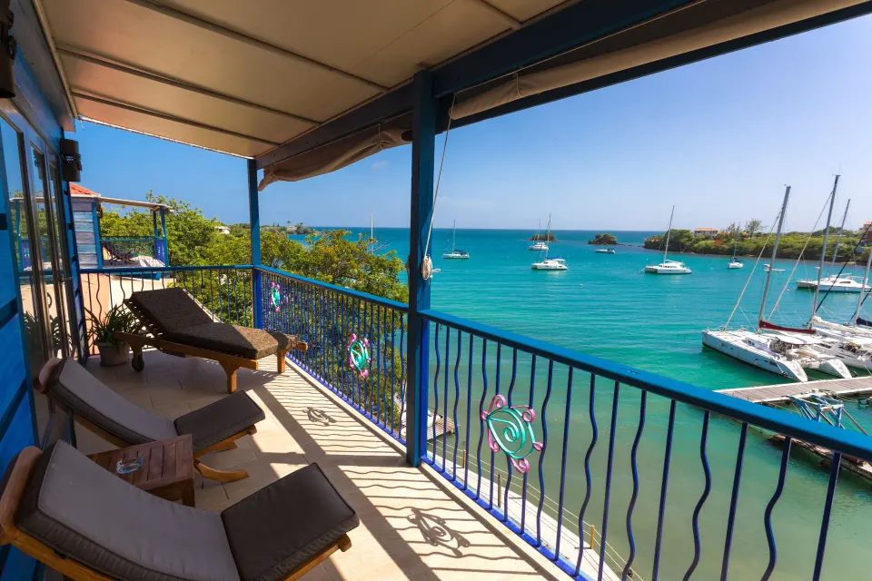 Waterfront Suite balcony with loungers and bay view at True Blue Bay Resort.
