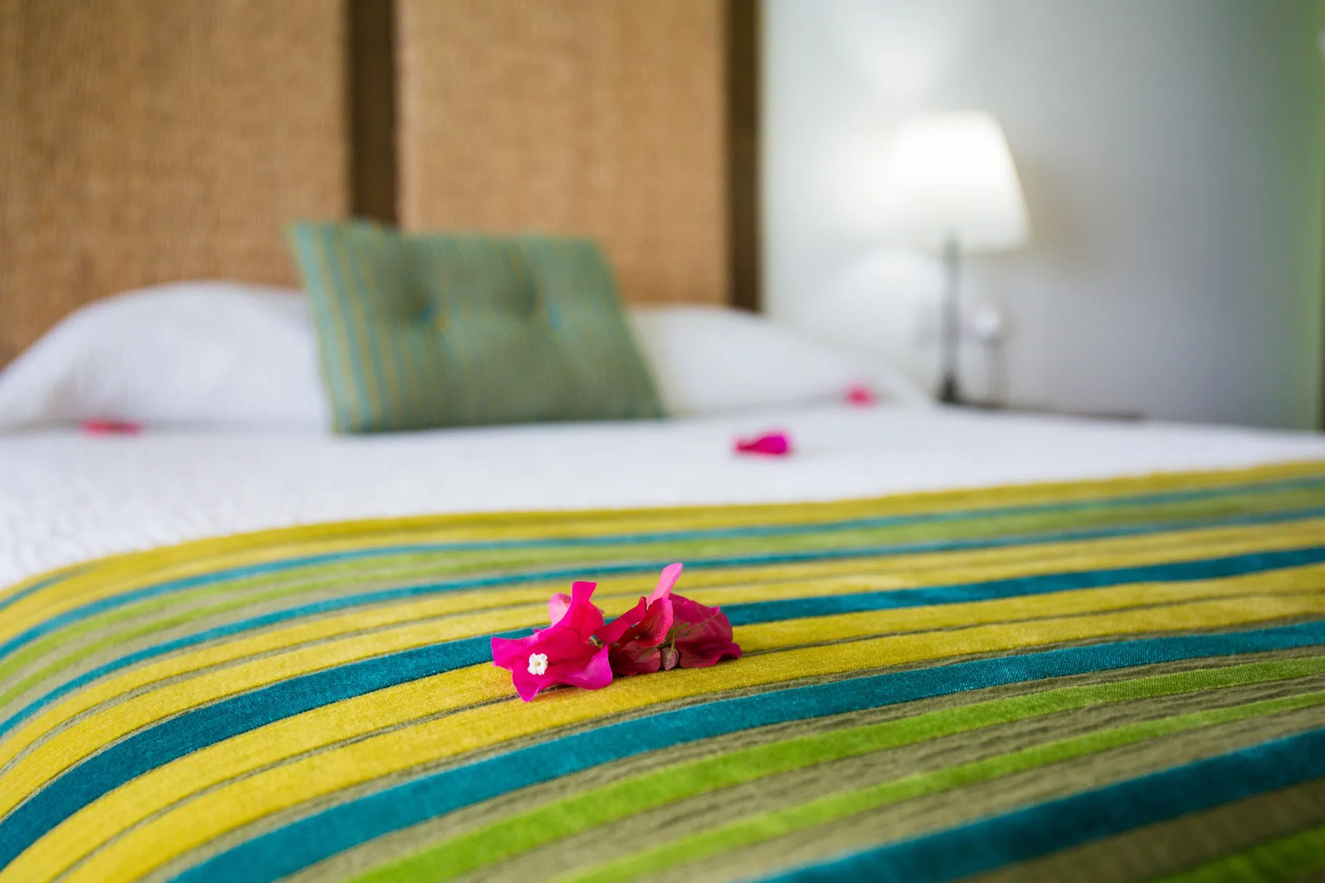 Waterfront Suite bed with striped runner and flowers at True Blue Bay Resort.