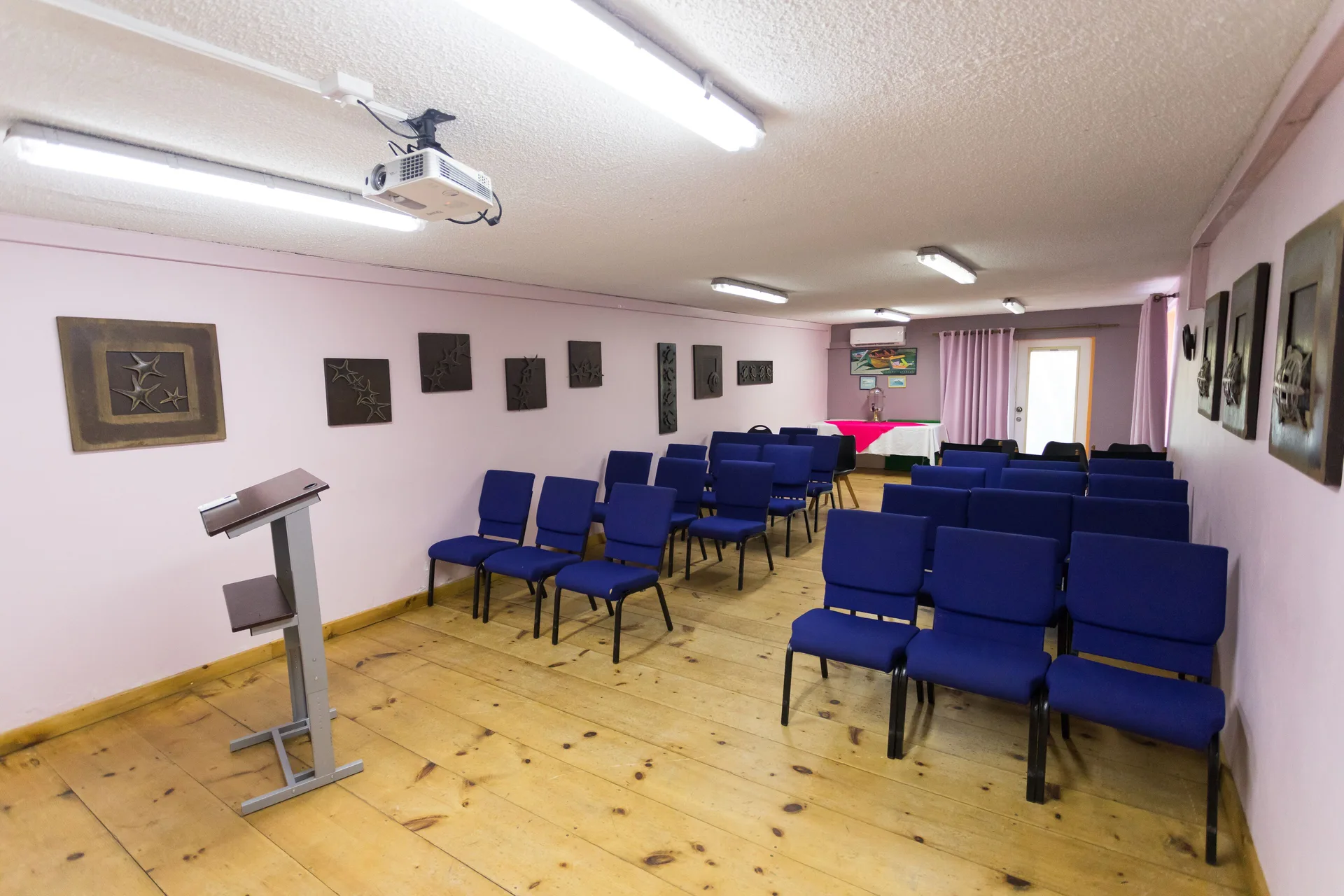 Meeting room with blue chairs and a lectern at True Blue Bay Resort.