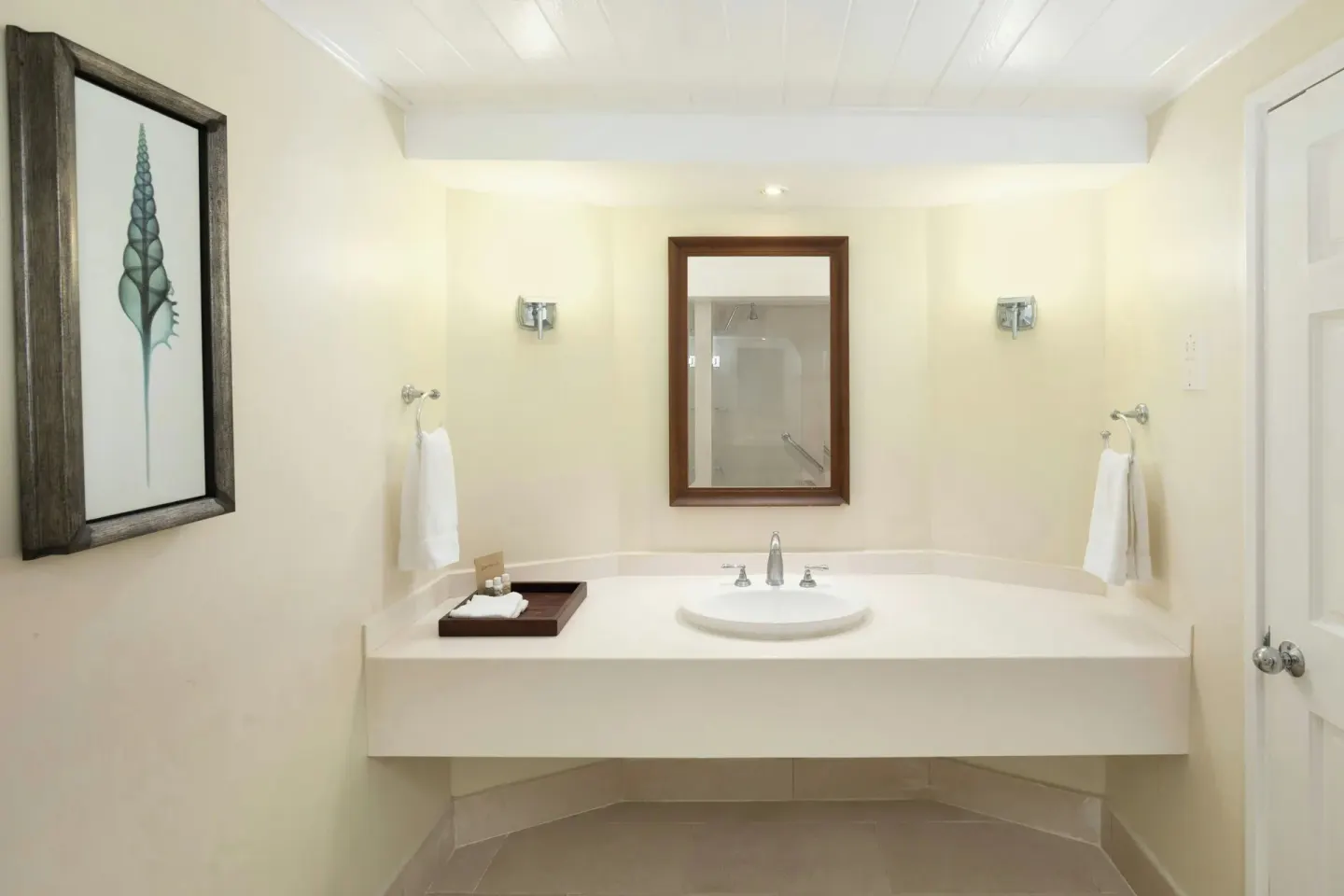 Bathroom vanity with mirror, towels and shell artwork at Turtle Beach.