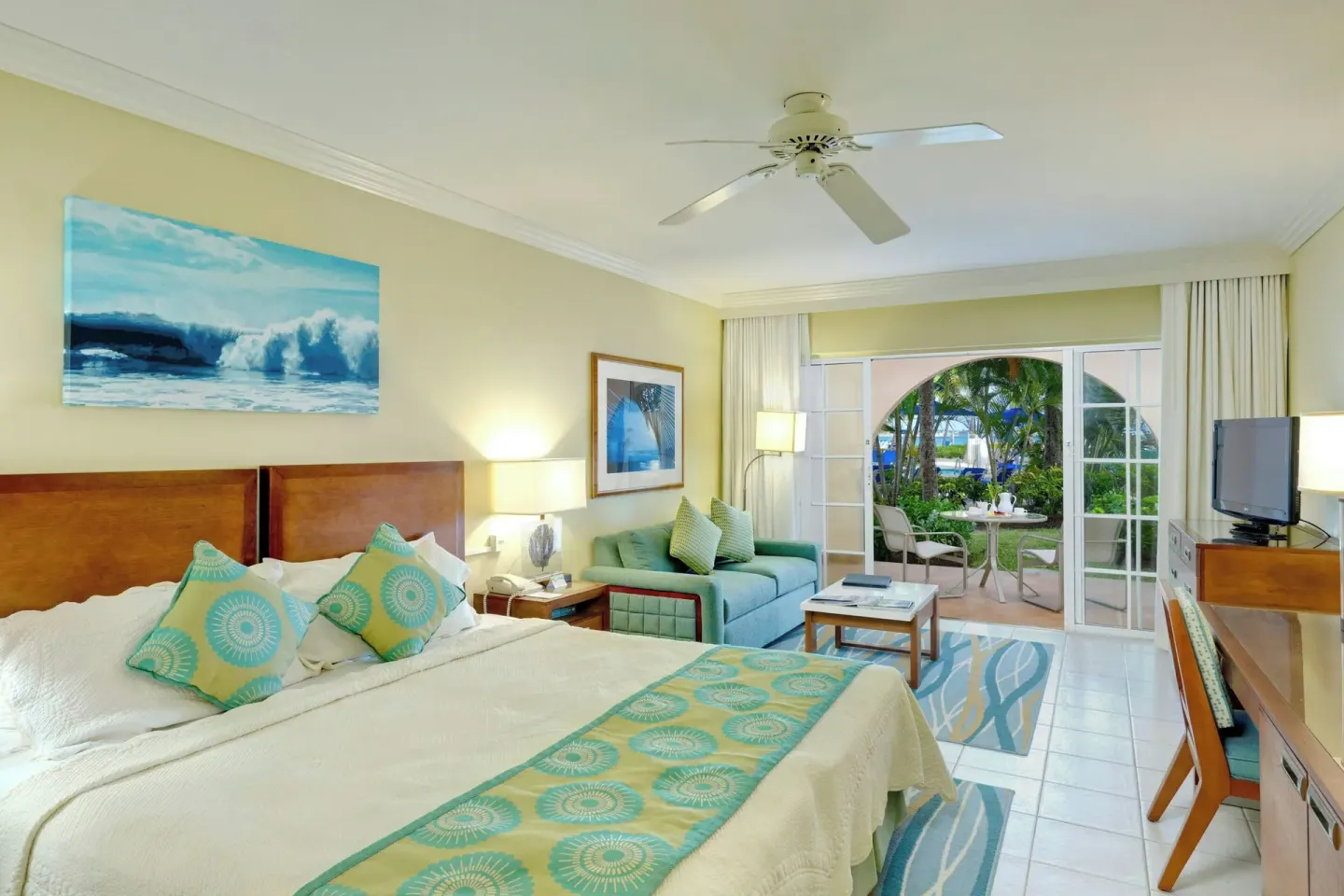 King bed guest room at Turtle Beach with sofa and patio doors to tropical landscaping.