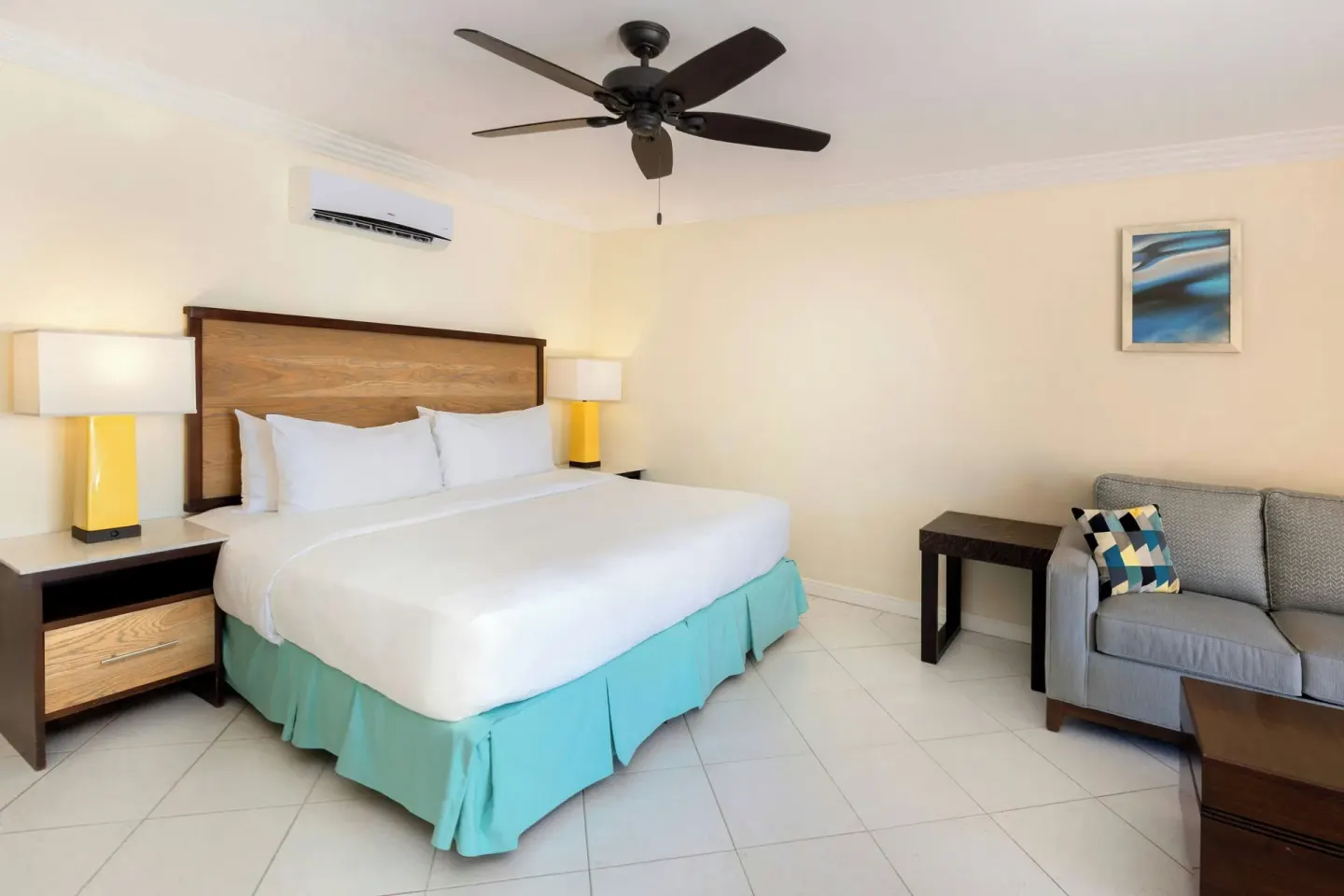 Guest room with king bed, sofa, side tables, and ceiling fan at Turtle Beach.