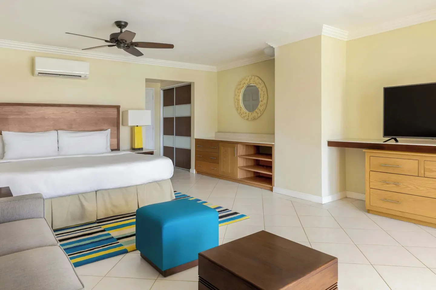 Guest room with king bed, sofa, ottoman, storage, and TV at Turtle Beach.