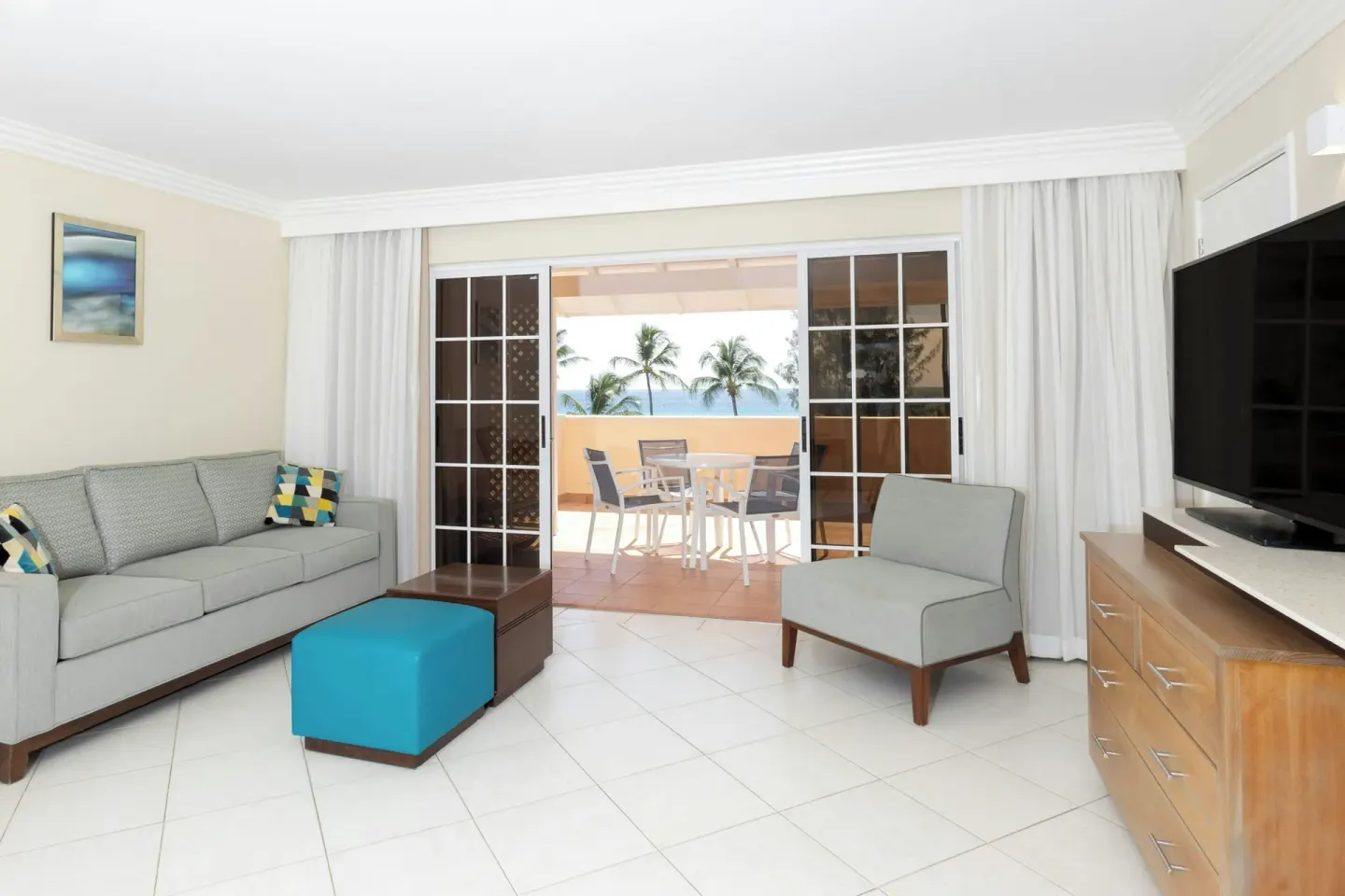 Living area at Turtle Beach opening to a terrace with ocean glimpses through sliding doors.