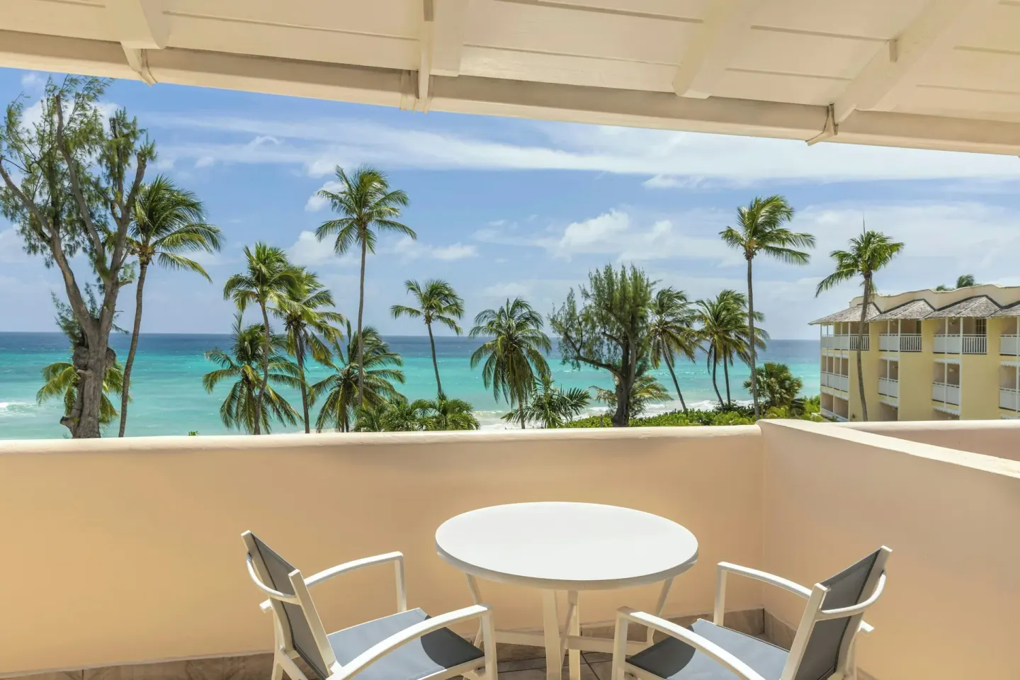 Balcony with table, chairs, palm trees, and ocean view at Turtle Beach.