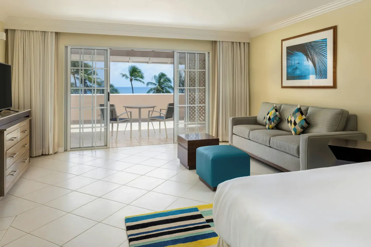 Guest room with bed, sofa, TV, and balcony ocean view at Turtle Beach.