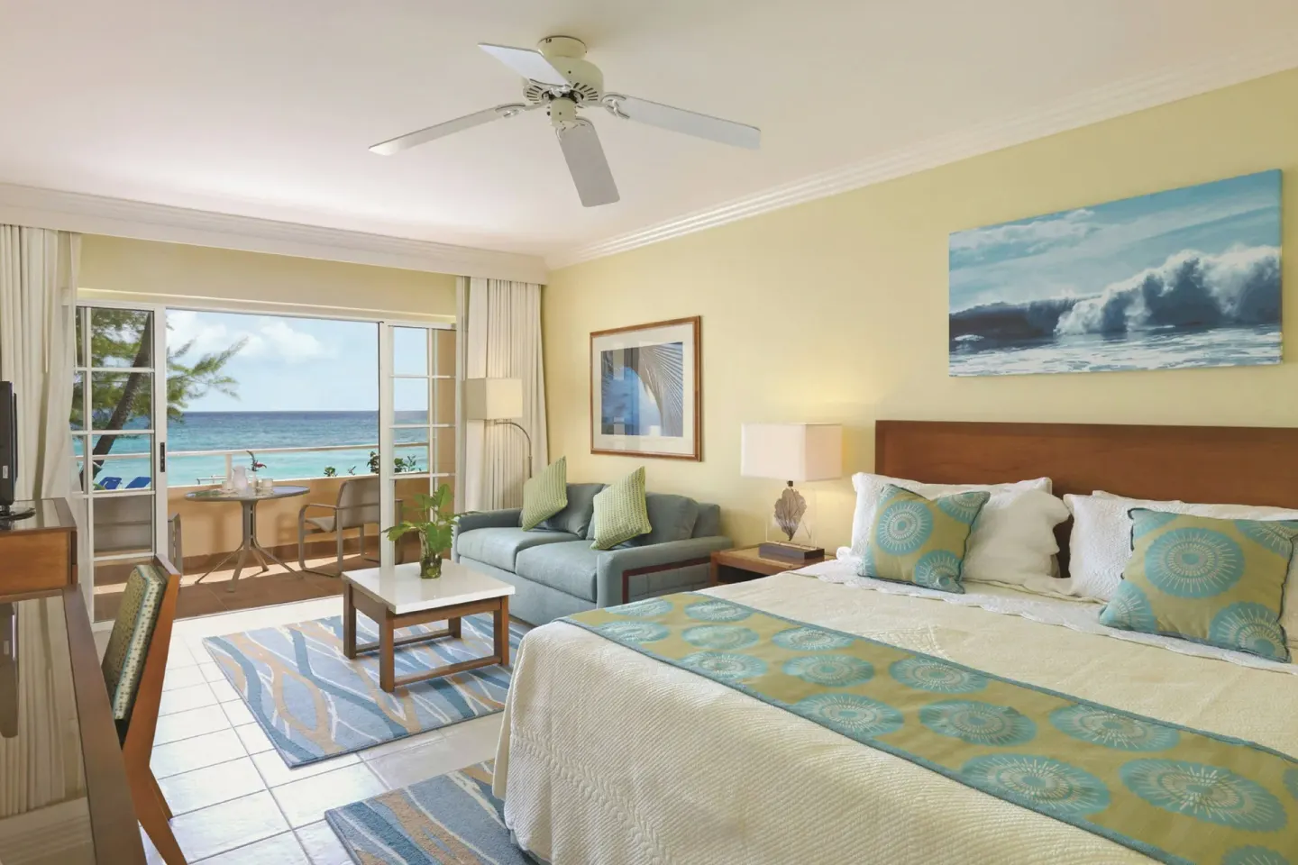 King bed guest room at Turtle Beach with sofa, balcony seating and ocean view.