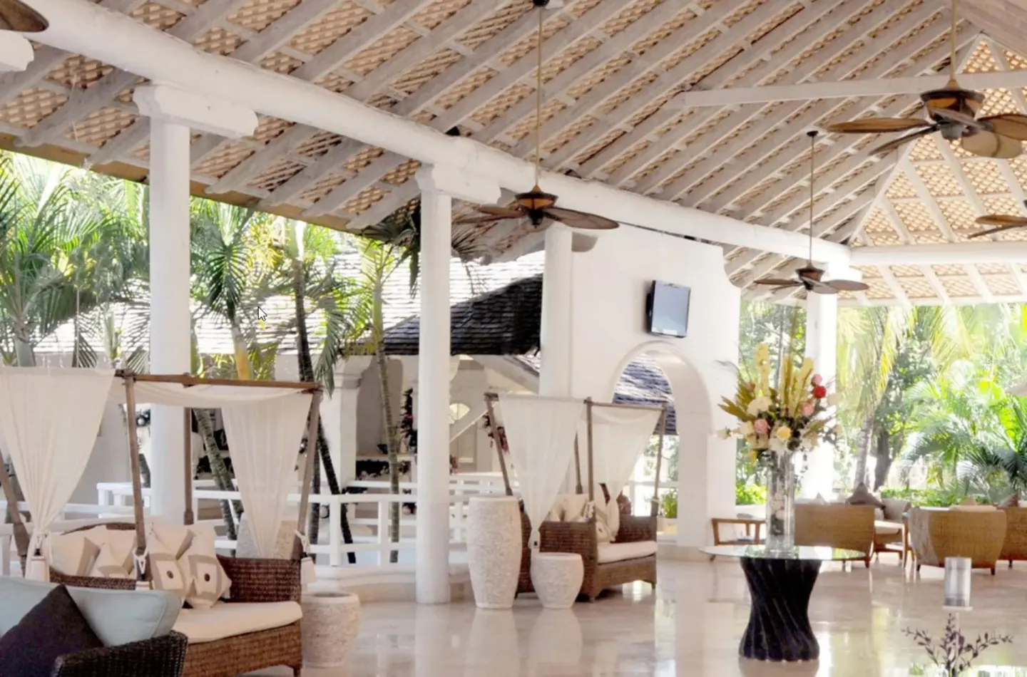 Open-air lobby lounge with white columns and wicker seating at Turtle Beach.