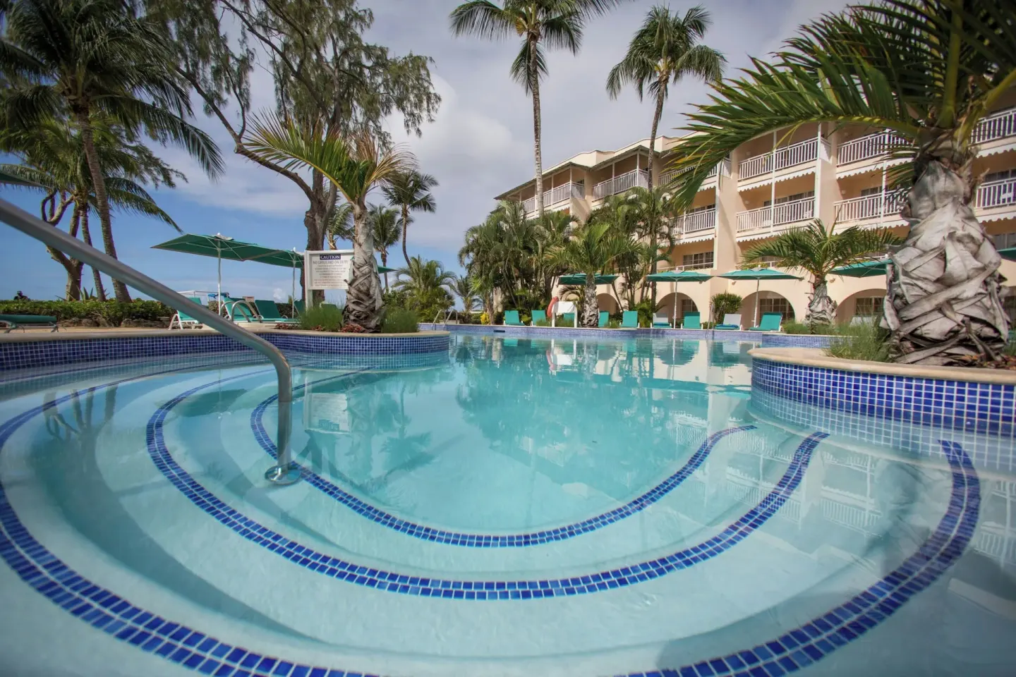 Pool steps with blue tile, palms, and resort balconies at Turtle Beach.