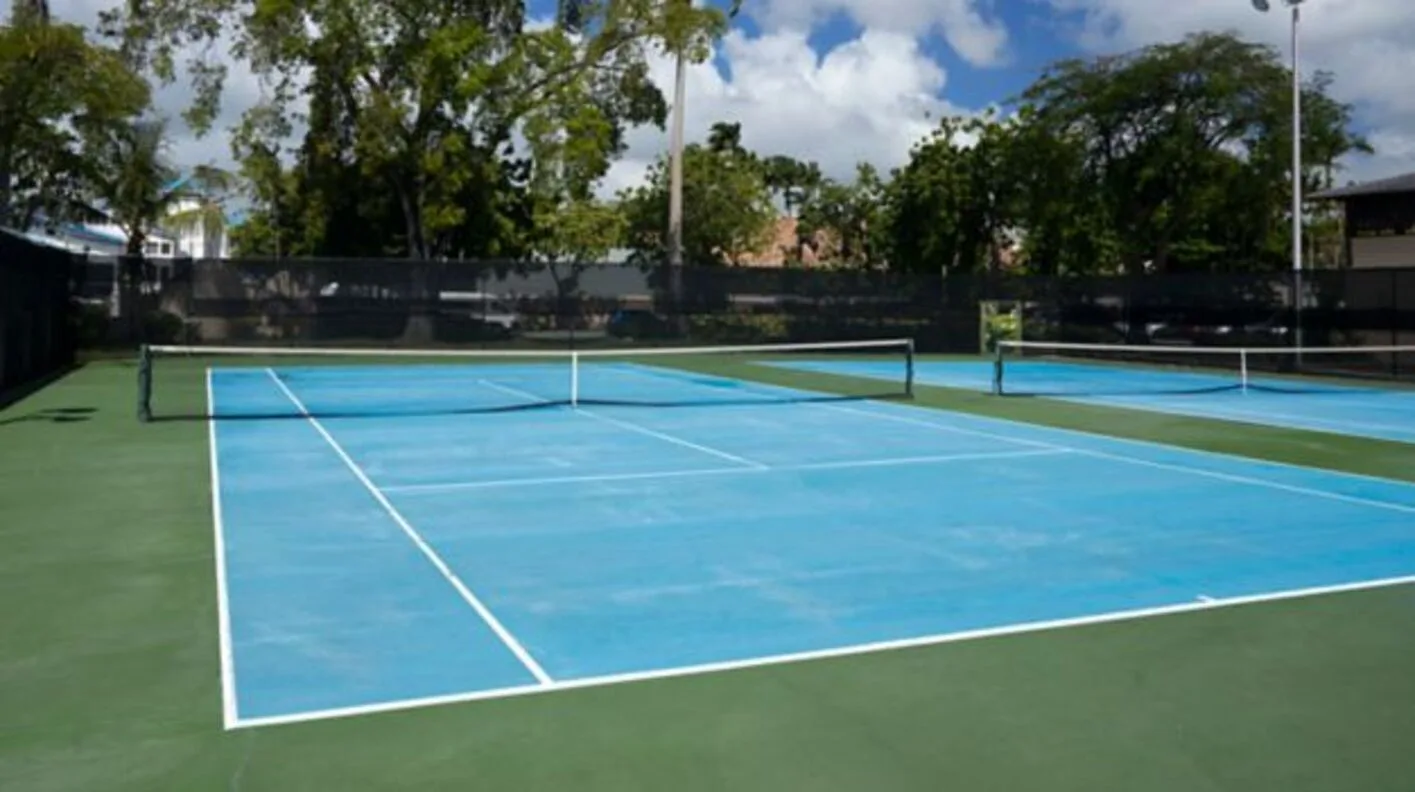 Two blue tennis courts with nets and trees at Turtle Beach.