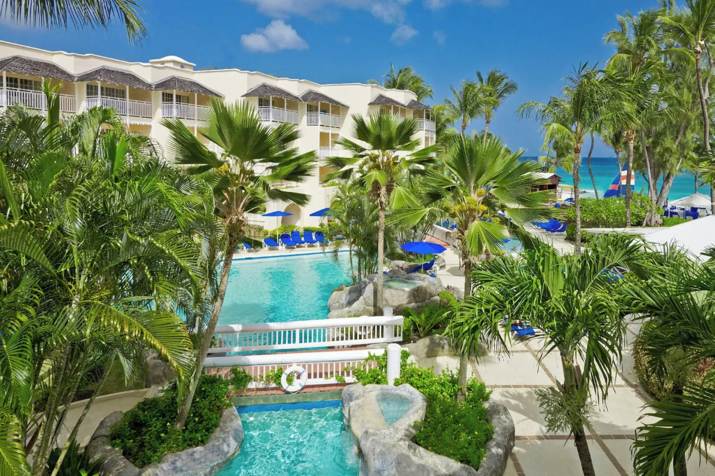 Tropical pool area with white bridge, palms, and ocean beyond at Turtle Beach.