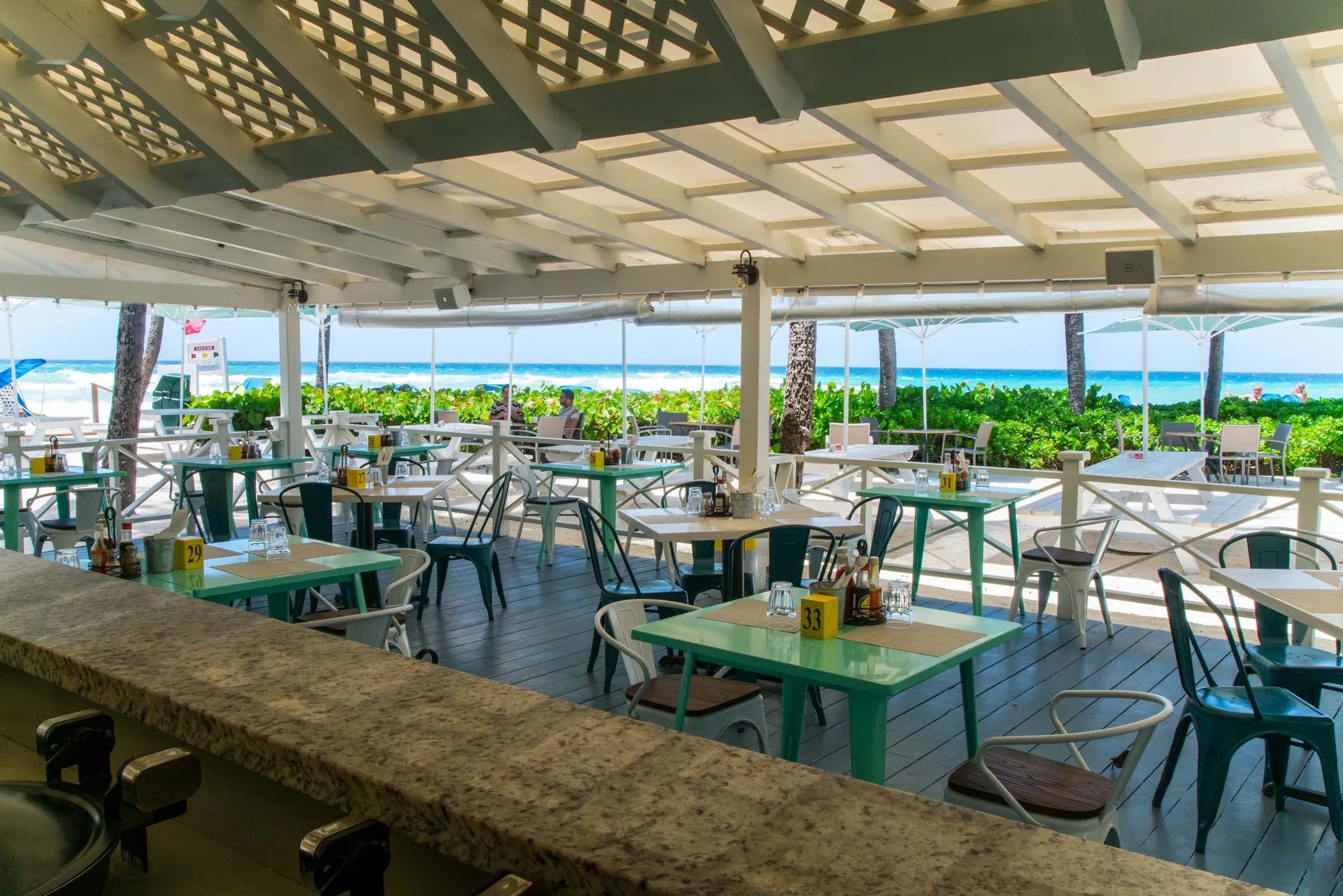 Covered beachfront dining terrace with turquoise tables at Turtle Beach.