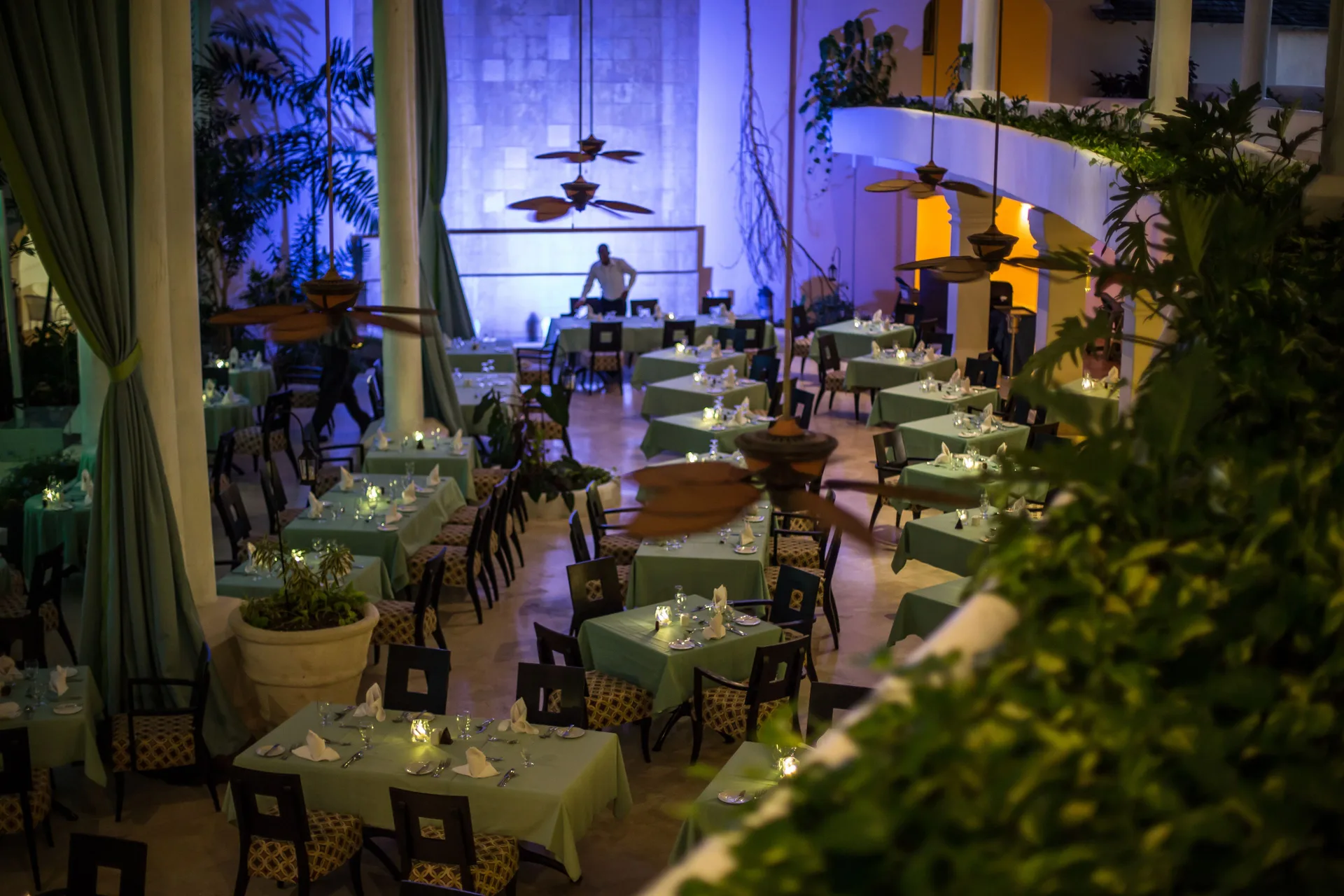 Candlelit dining room with teal tablecloths and plants at Turtle Beach.