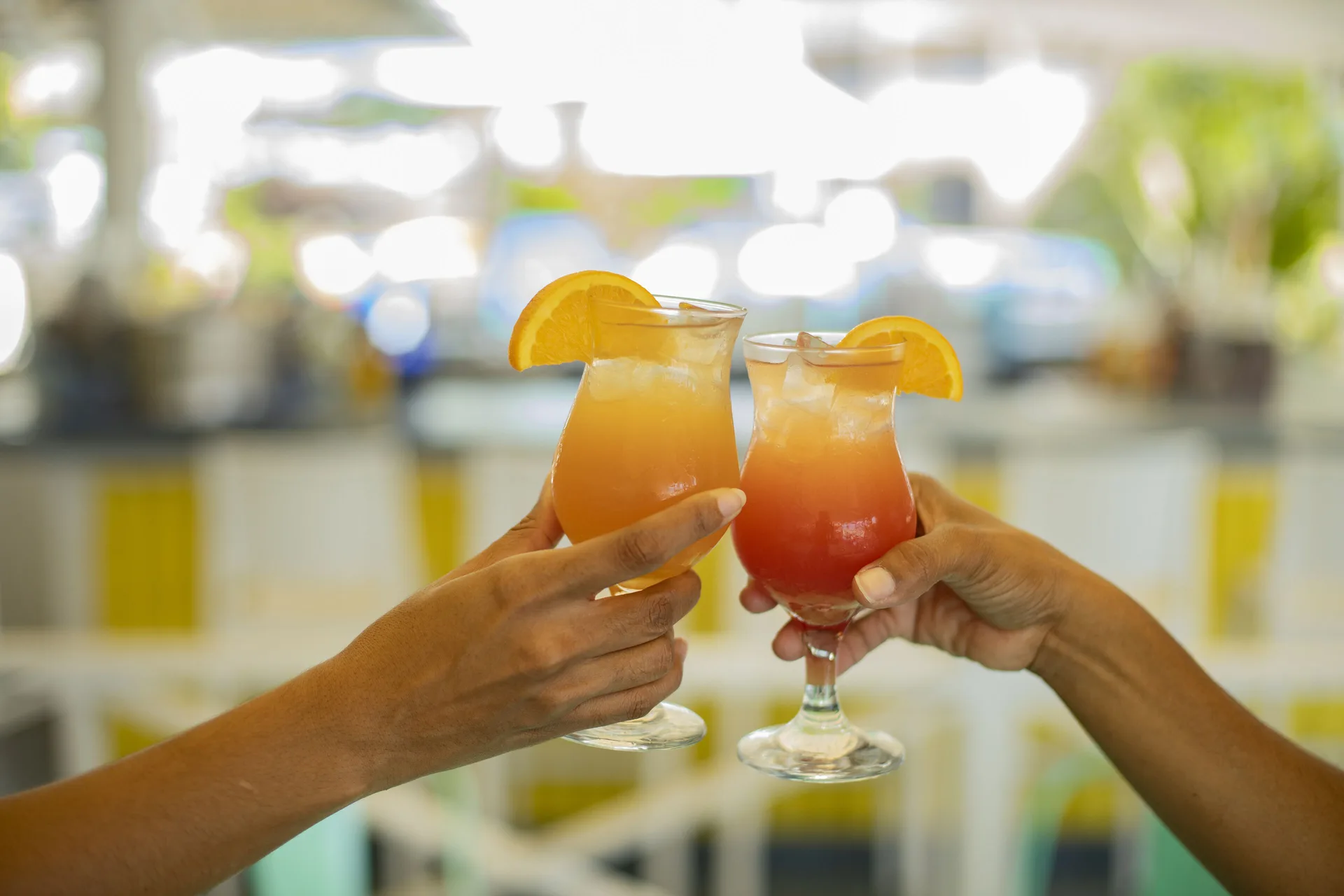 Two tropical drinks with orange garnishes being raised at Turtle Beach.