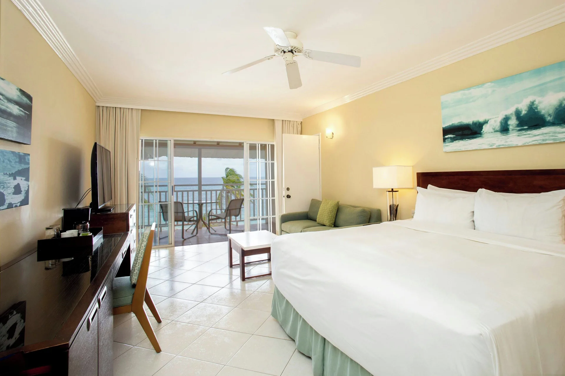 King bed in a Junior Suite ocean view guest room at Turtle Beach with sofa and balcony.
