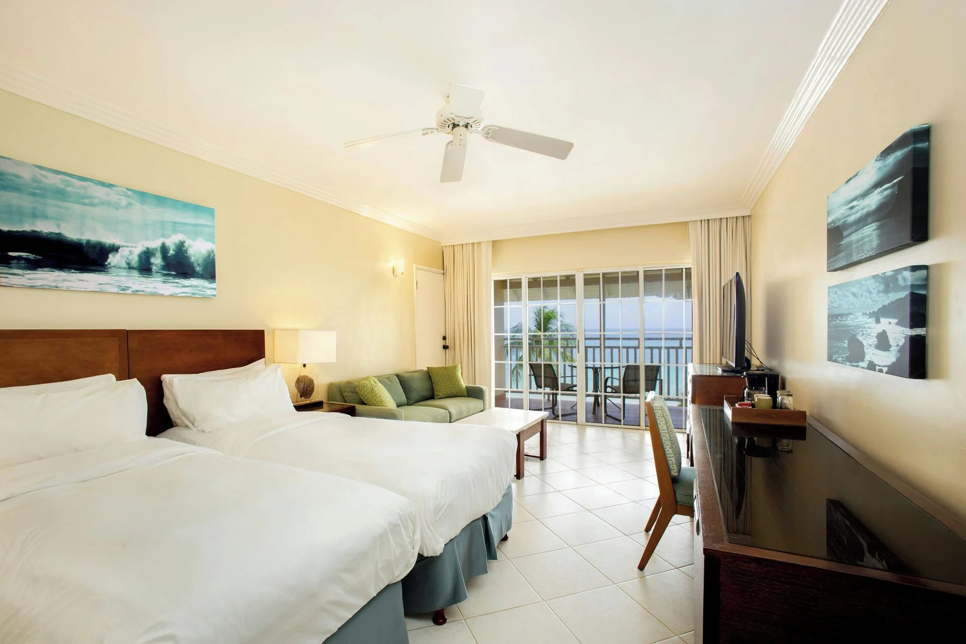 Two beds in a Junior Suite ocean view guest room at Turtle Beach with balcony seating.