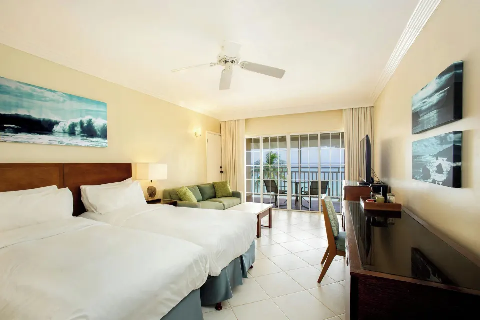 Two-bed Junior Suite ocean view room at Turtle Beach with sofa, desk, and balcony.