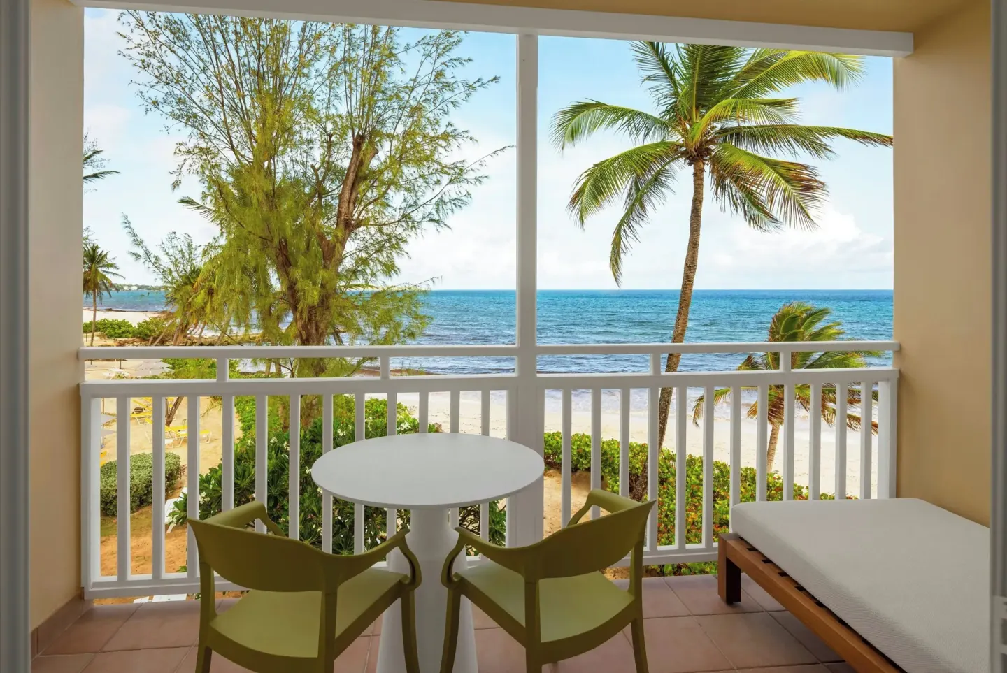 Ocean-view balcony with table, chairs and daybed at Turtle Beach.