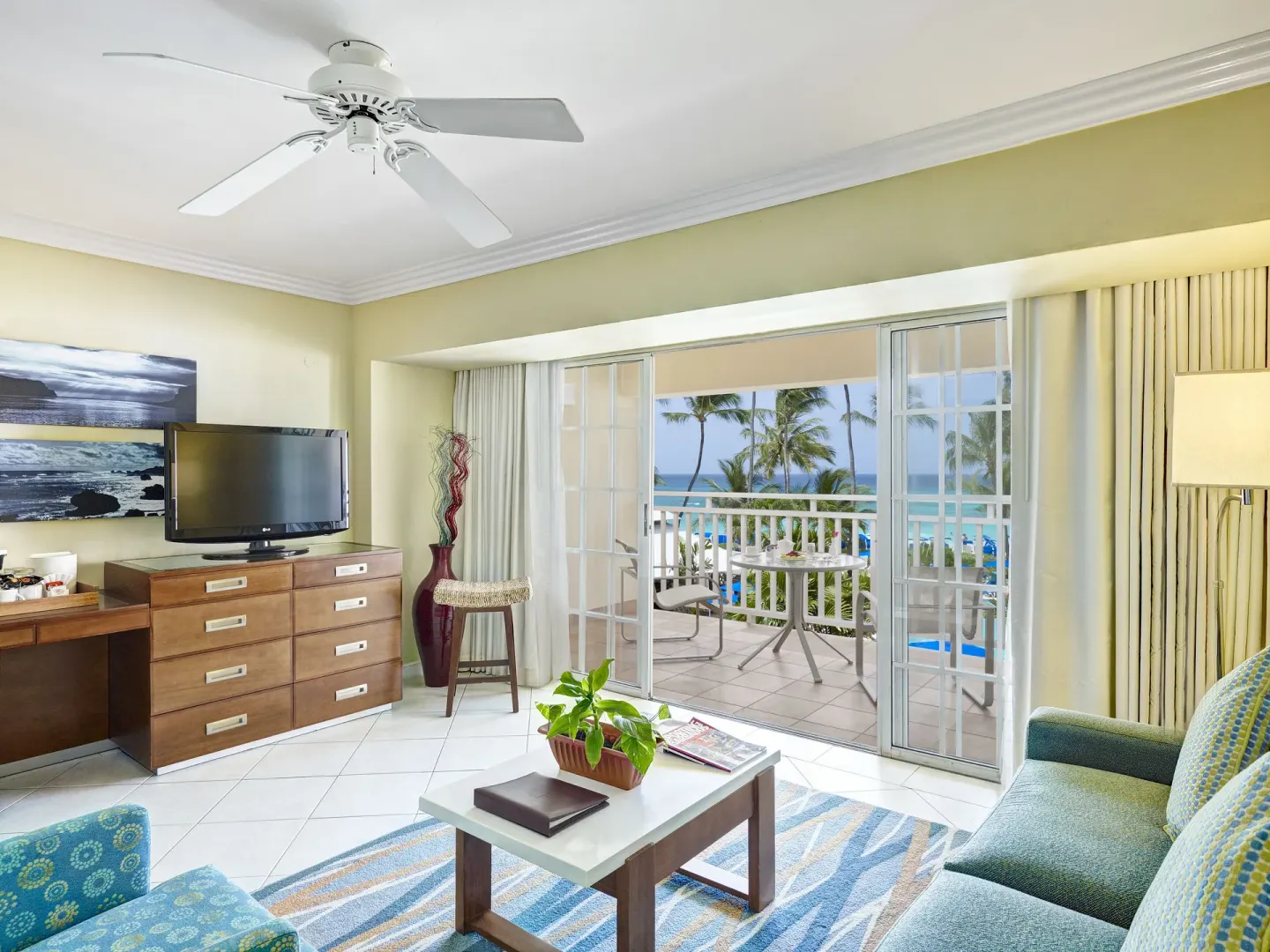 Sitting area with sofa, TV, balcony, and ocean view in a suite at Turtle Beach.