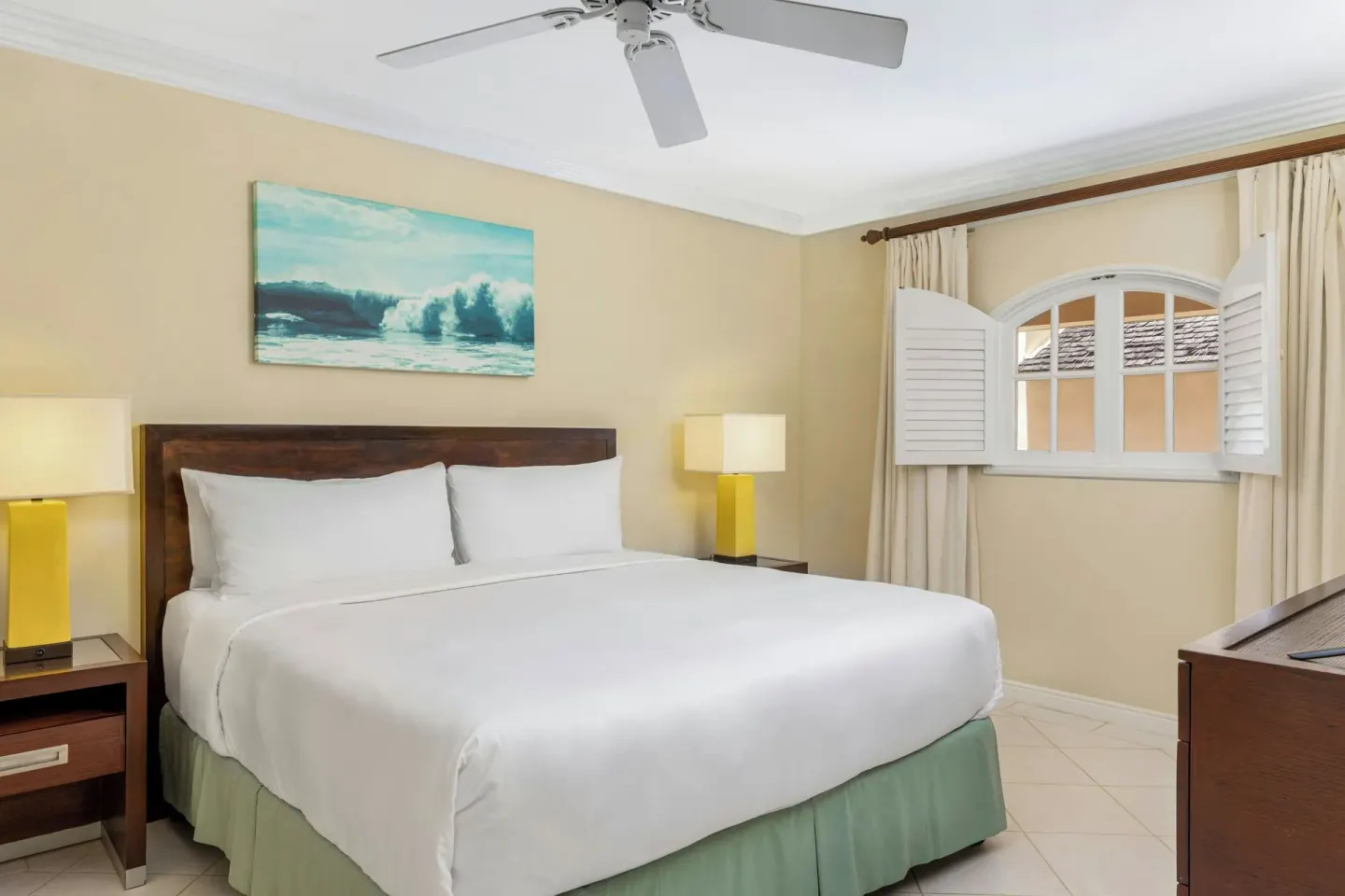 Suite bedroom with king bed, shuttered window, and ceiling fan at Turtle Beach.