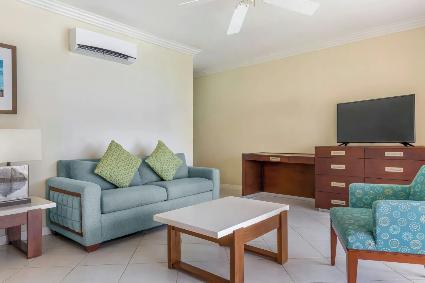 Suite living area with sofa bed, armchair, coffee table, and TV at Turtle Beach.