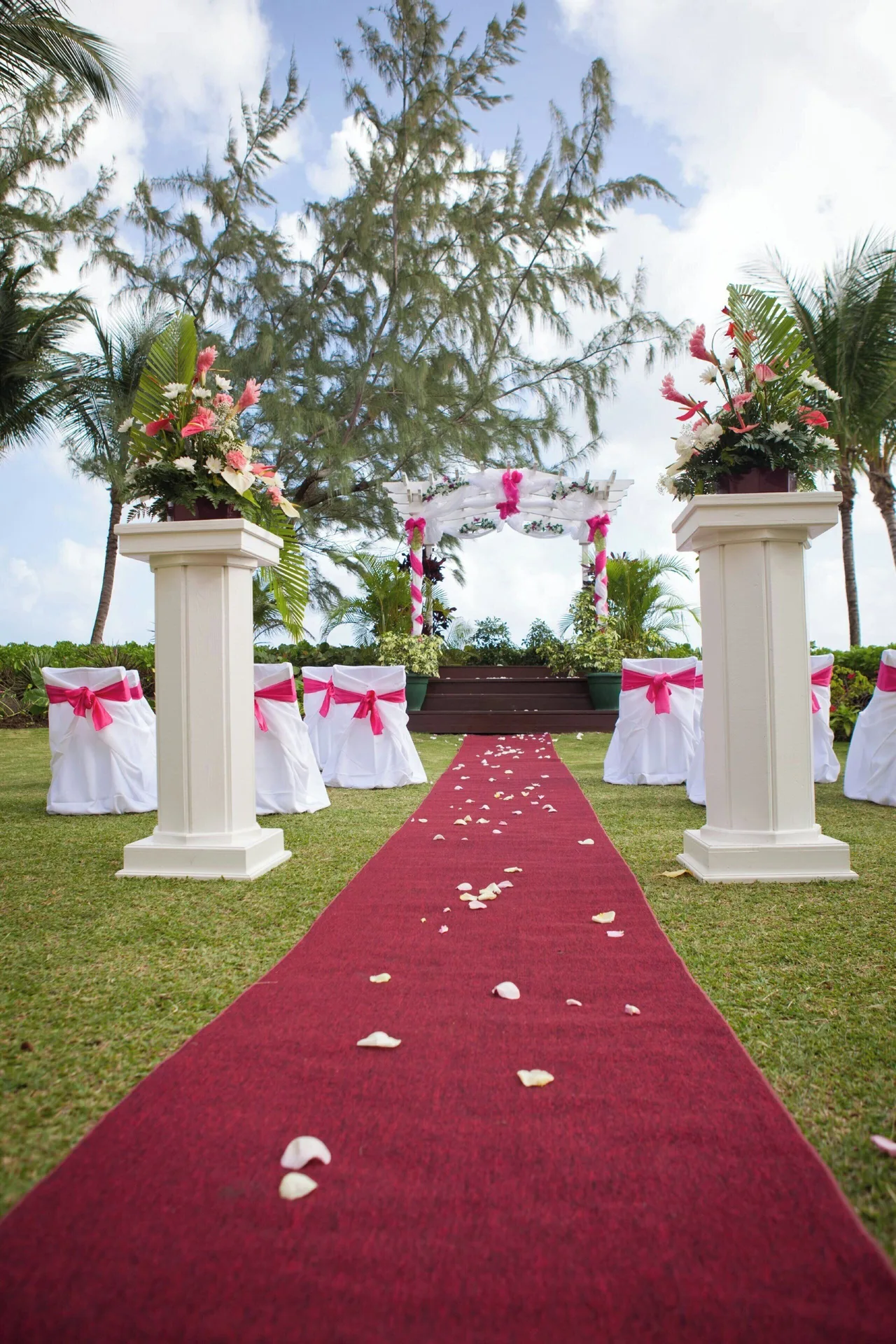 Outdoor wedding aisle with red carpet and floral pillars at Turtle Beach.