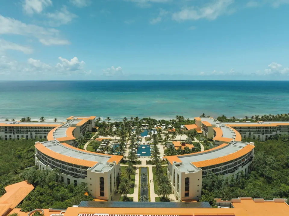 Aerial frontal view of the crescent-shaped Unico Hotel Riviera Maya resort and beachfront
