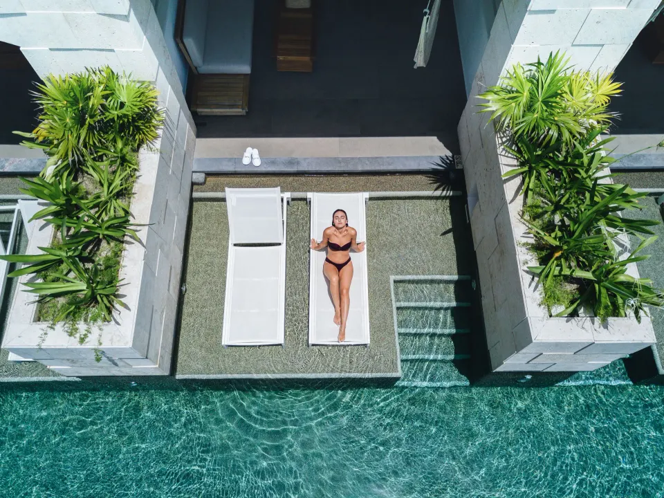 Overhead view of a guest sunbathing on a poolside ledge at Unico Hotel Riviera Maya