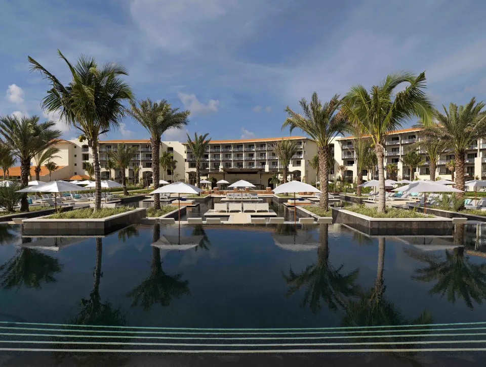 Central resort pool framed by palm trees and hotel buildings at Unico Hotel Riviera Maya