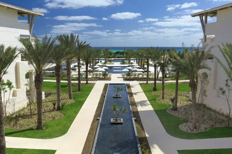 Central reflecting canal and palm-lined walkway facing the ocean at Unico Hotel Riviera Maya