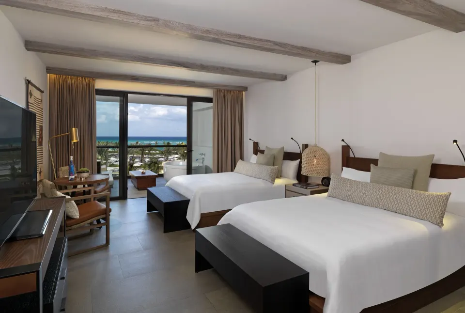 Bright guest room with two beds and ocean view balcony at Unico Hotel Riviera Maya