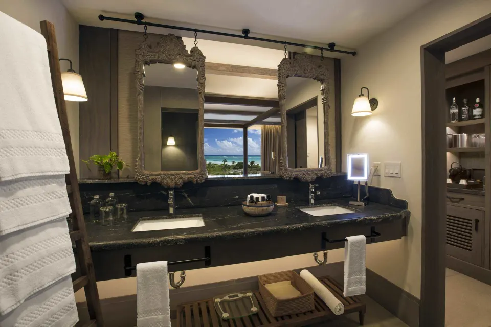 Double vanity with ornate mirrors and a view to the grounds at Unico Hotel Riviera Maya