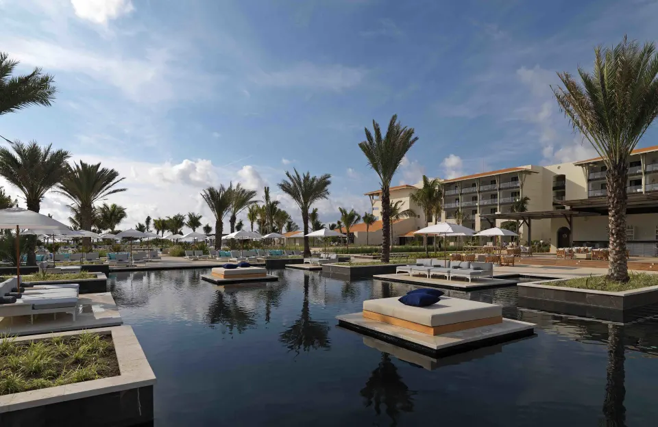 Pool area with floating daybeds and palm trees at Unico Hotel Riviera Maya