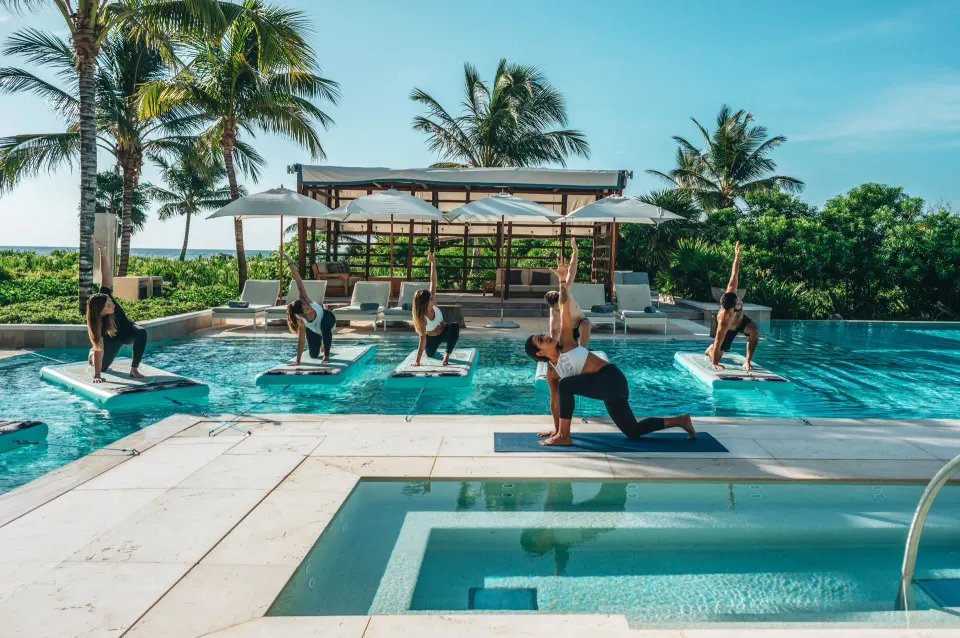 Outdoor pool class with floating yoga mats and instructor at Unico Hotel Riviera Maya