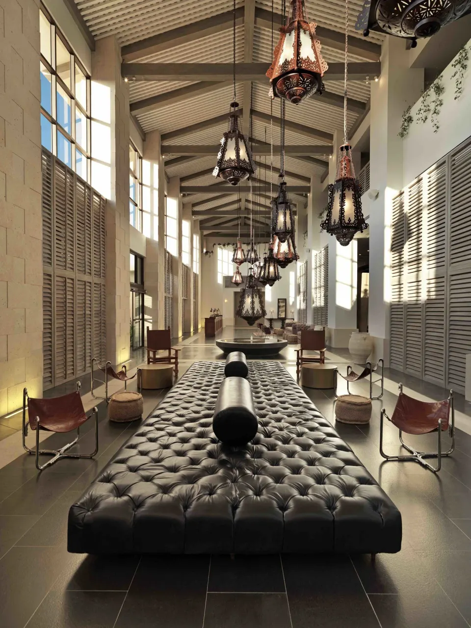 High-ceilinged lobby with tufted bench and hanging lanterns at Unico Hotel Riviera Maya