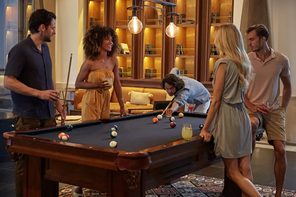 Group of guests playing pool in a social lounge at Unico Hotel Riviera Maya