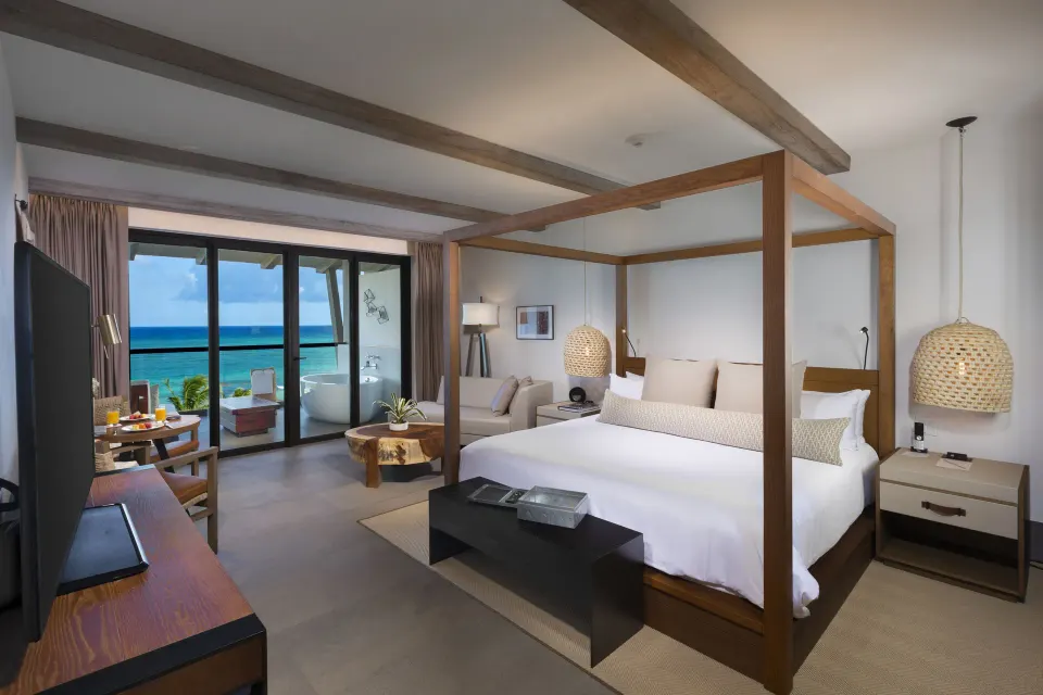 Bright junior suite with four-poster king bed and balcony at Unico Hotel Riviera Maya