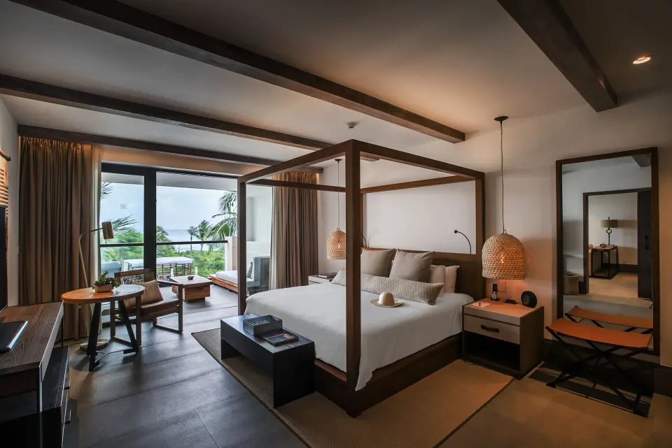 Cozy guest room with king bed, balcony and dark wood floors at Unico Hotel Riviera Maya