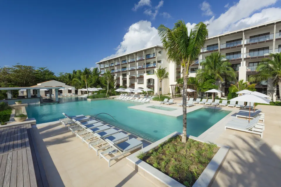 Main resort pool with submerged loungers and palm trees at Unico Hotel Riviera Maya
