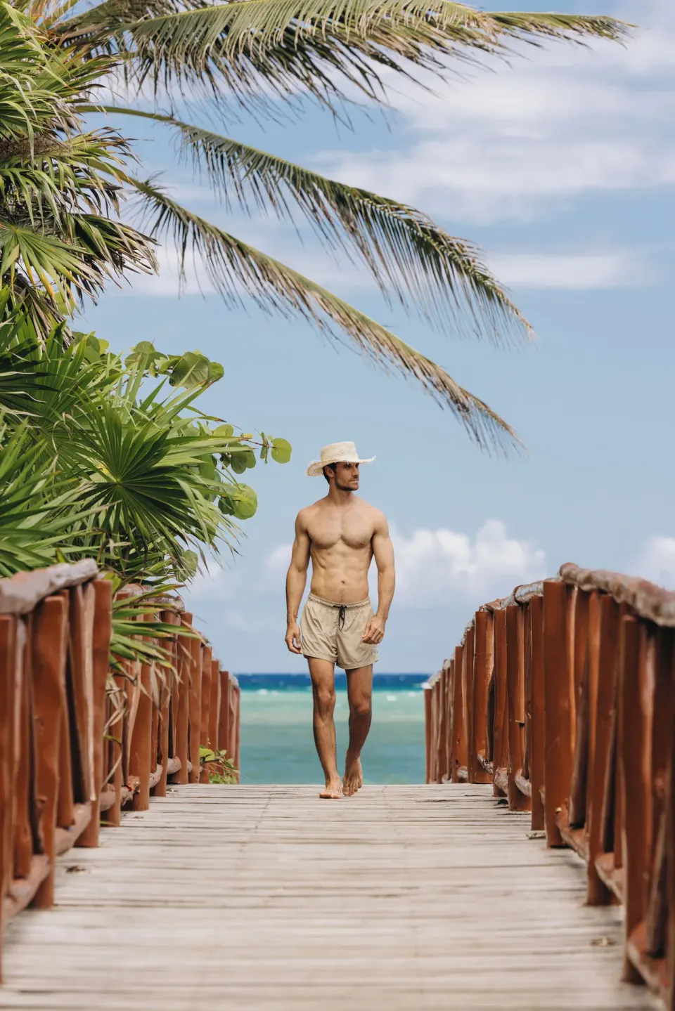 Man walking alone on a beachfront wooden bridge toward the ocean at Unico Hotel Riviera Maya