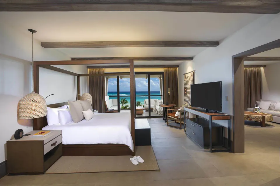 Large suite with king bed, sofa and balcony overlooking the ocean at Unico Hotel Riviera Maya