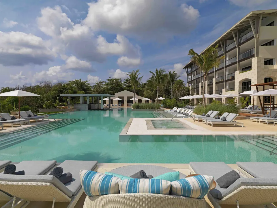 Light-blue resort pool with shallow entry and cushioned loungers at Unico Hotel Riviera Maya