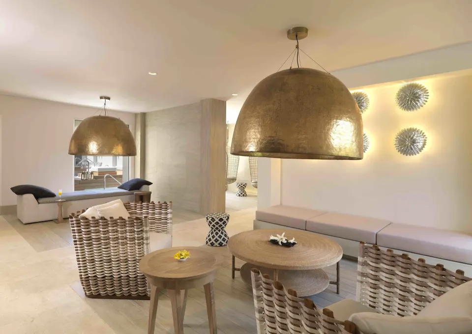 Bright spa lounge with woven chairs and large dome lights at Unico Hotel Riviera Maya